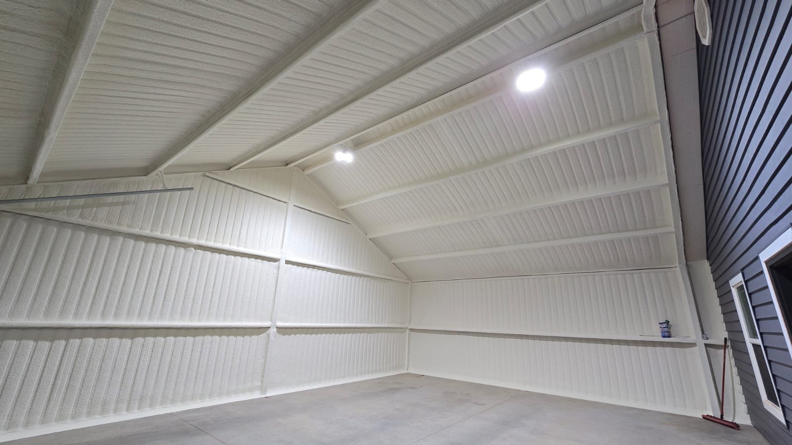 Completed spray foam insulation installation in a finished pole barn interior with overhead lighting installed